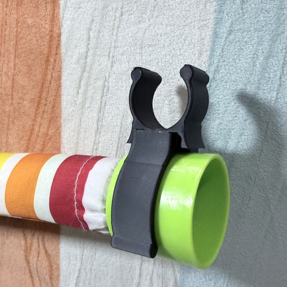 Black rod holder clip gripping a colorful backdrop stand rod