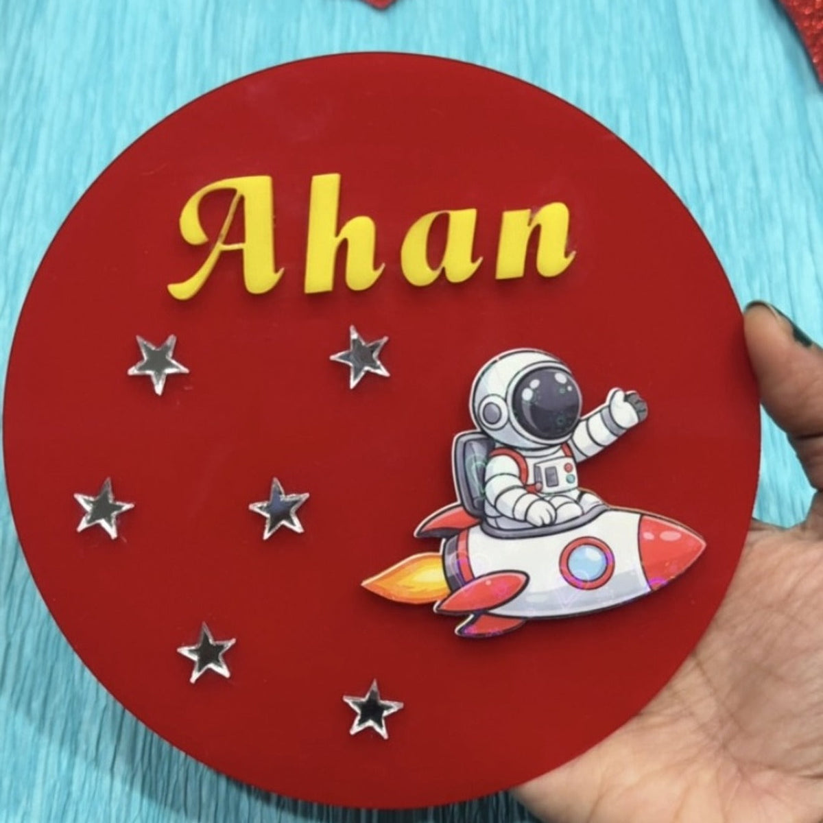 Personalized kids room sign board — red round sign with yellow name Ahan, astronaut, rocket and stars
