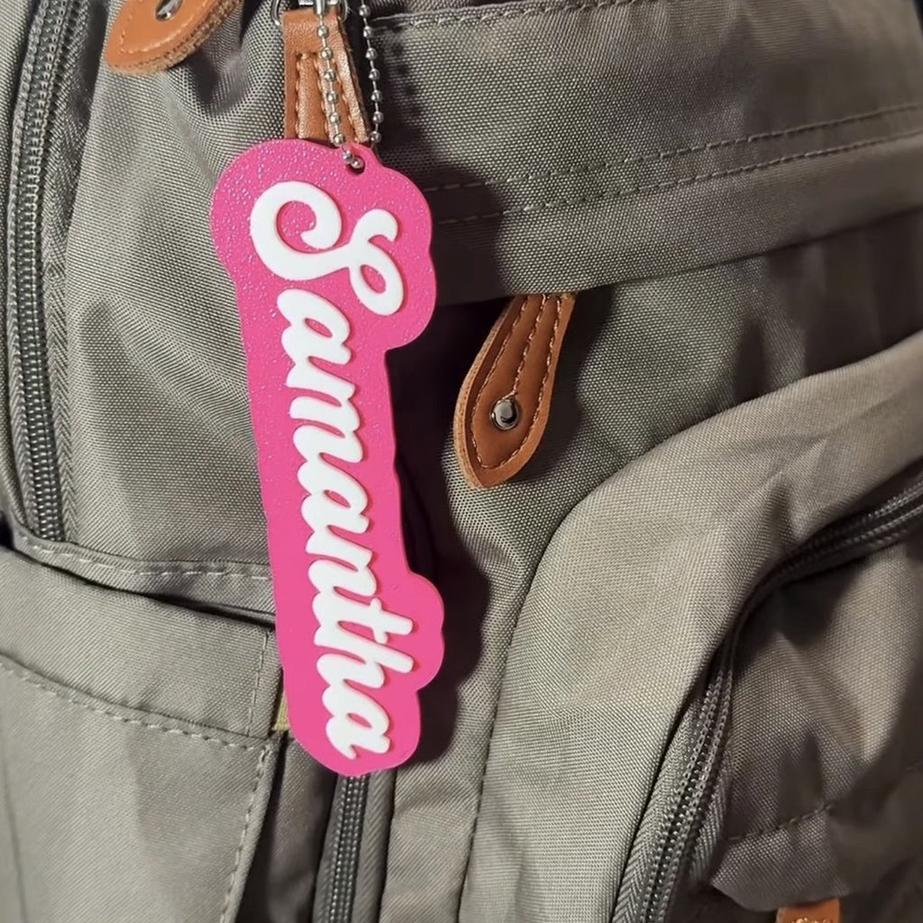 Personalized 3D printed name bag tag — pink tag with white name Samantha hanging on a backpack