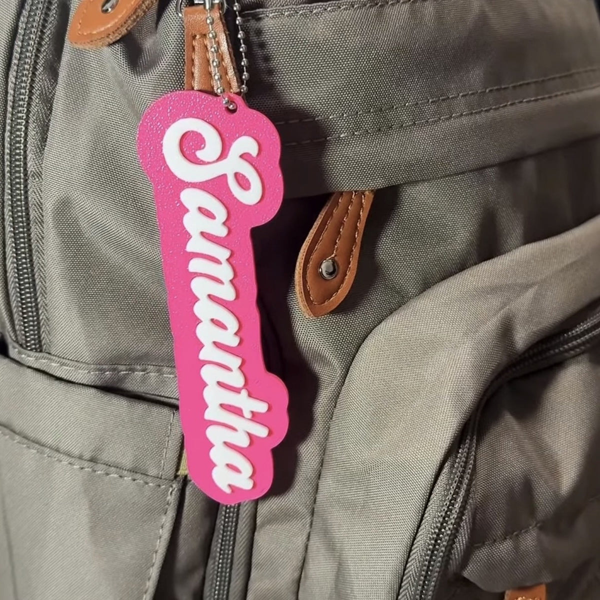 Personalized 3D printed name bag tag — pink tag with white name Samantha hanging on a backpack